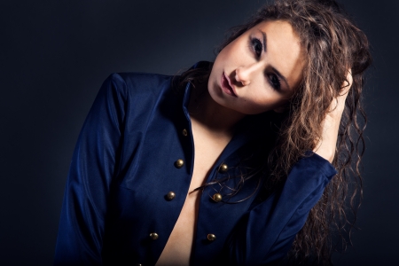 portrait of a pretty caucasian woman in blue coat in studio on dark backgroundの写真素材