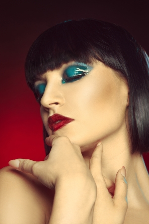 Portrait of sweet young woman with professional make up in studio on red backgroundの写真素材