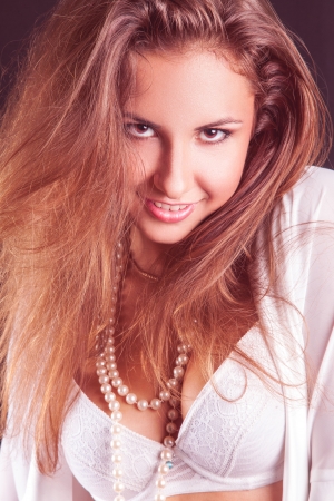 Sweet adult woman smilng at camera in studio in white clothesの写真素材