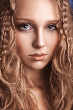 Portrait of charming young woman with curly brown hair in studioの写真素材