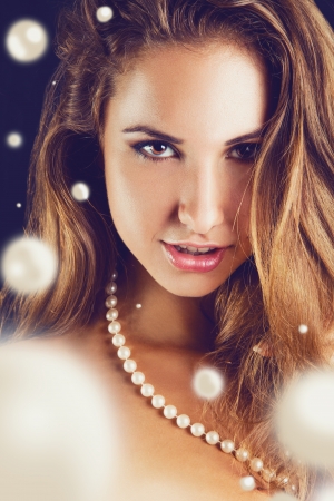 Close up portrait of lovely female with lots of pearls in studio on black backgroundの写真素材
