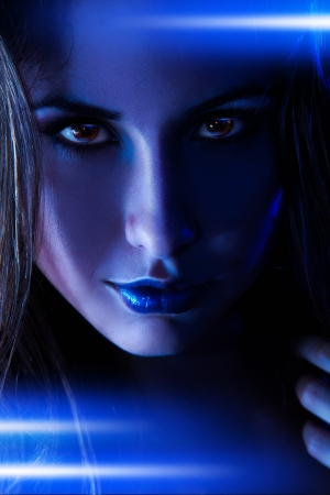 Portrait of nice woman with blue shining lines in studioの写真素材
