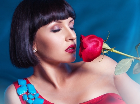 Cute brunette with red rose on blue background in studioの写真素材