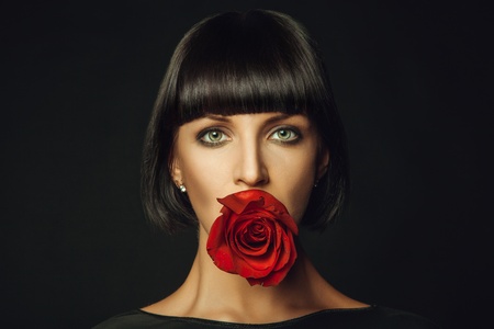 Adult female with red rose in mouthの写真素材