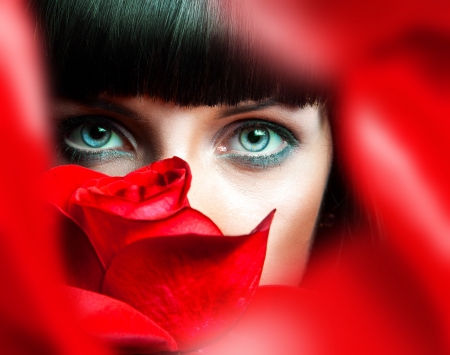 Lovely brunette behind red rose in studioの写真素材