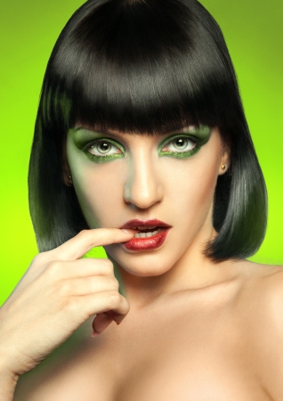 Charming brunette looking at camera in studio on green backgroundの写真素材