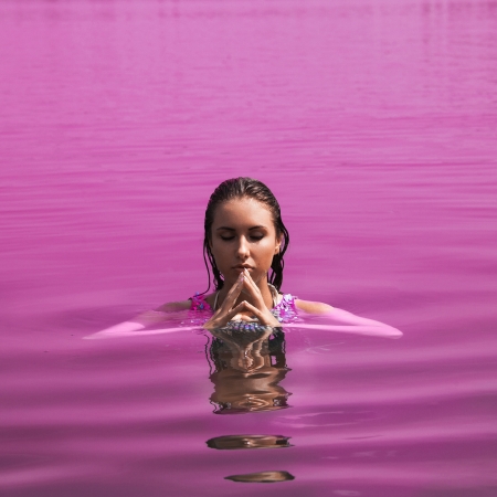 Adult woman with closed eyes in pink waterの写真素材