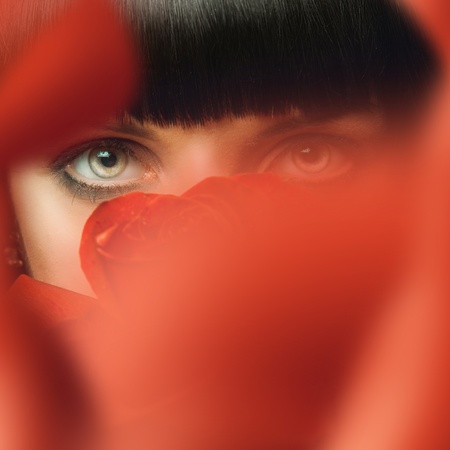 Brunette behind red roseの写真素材