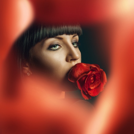 Female looking away beahind red rosesの写真素材