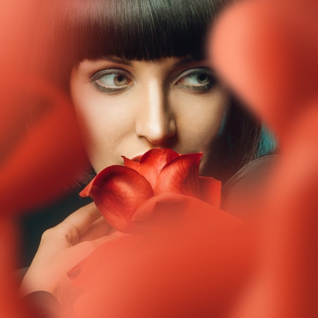 Brunette behind red roseの写真素材
