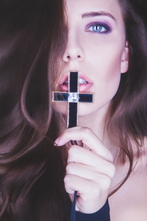 portrait of a beautiful girl with cross near mouth in studioの写真素材