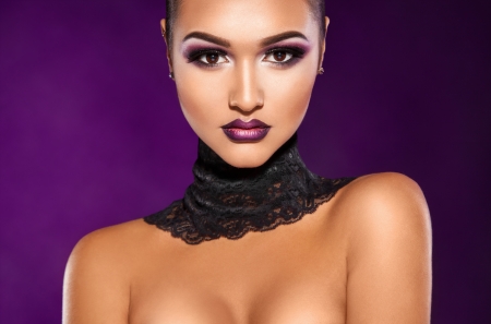 Fashion beautiful woman in studio on purple background looking at cameraの写真素材