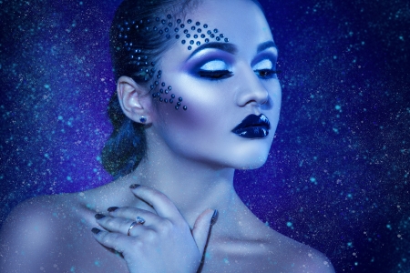 Winter portrait of beautiful woman in studio with snow in cold tones