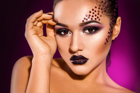 Sensual girl with make up and her hand near head in studioの写真素材