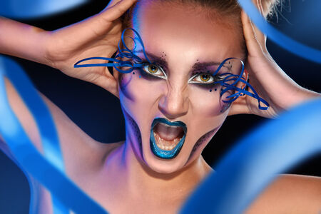 adult female screaming on camera with creative make up face in studioの写真素材