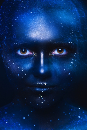 Blue tones portrait of cute woman with dark face art in studioの写真素材