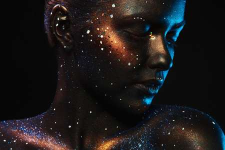 Portrait of woman with closed eyes and dark face art in studioの写真素材