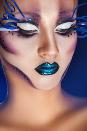 sexy female with creative make up in studio on blue backgroundの写真素材