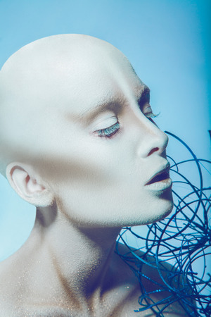 Bald woman with closed eyes in studio on blue backgroundの写真素材