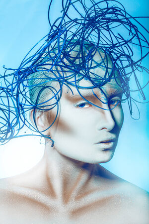 Beautiful woman with creative hairstyle and body art on blue backgroundの写真素材