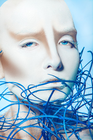Portrait of sexy girl with white body art on blue background in studioの写真素材