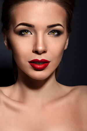 Beautiful woman with green eyes on dark background in studioの写真素材