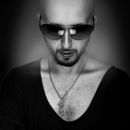 Black and white photo of strong caucasian man with beard and sunglasses in studioの写真素材