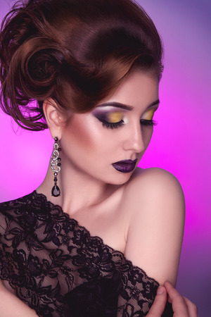 Vertical photo of elegance adult girl with creative hairstyle and make up on pink in studioの写真素材