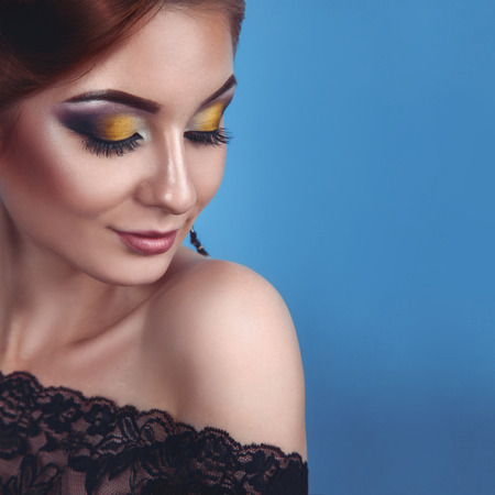 Square portrait of sexy young adult woman on blue in studioの写真素材
