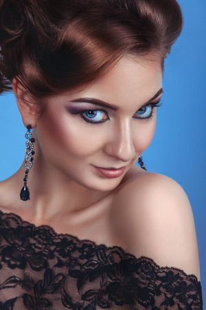 Luxury fashion woman with accessories and make up on blue in studioの写真素材