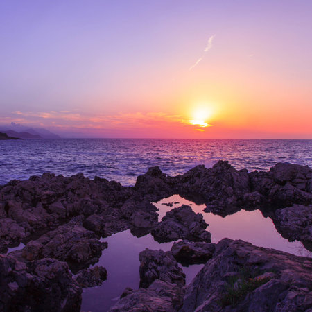 square photo of sunset on rocky beachの写真素材
