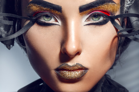 Close up portrait of charming adult woman with gold lips in studio