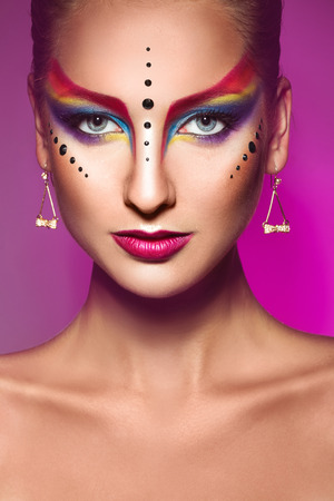 Portrait of fashion model with multicolor make up on purple background in studioの写真素材