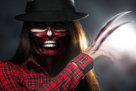 Scary halloween portrait of woman with knifes in hand in studio
