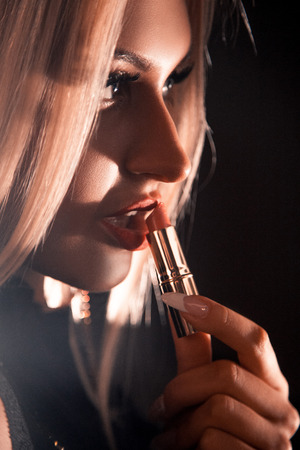 Cutie young blonde that paints red lipstick. Studio shotの写真素材