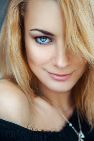 Fashionable young blonde girl with blue eyes looking at camera and smiling. vertical color imageの写真素材