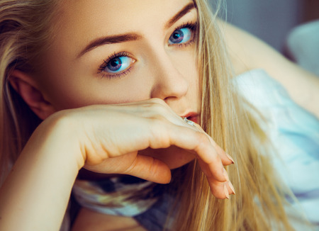 Stunning young blonde woman looking at camera with blue eyes indoorsの写真素材