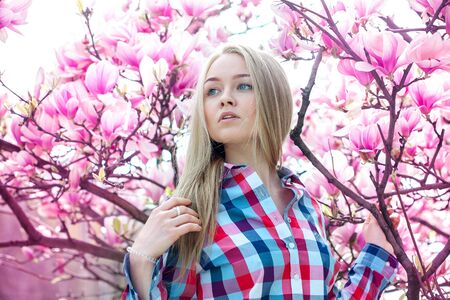 dreamy blonde girl looking to the side near the spring blooming trees outdoor at parkの写真素材