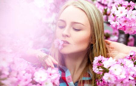 Bright charming woman with flower in mouth. Spring timeの写真素材