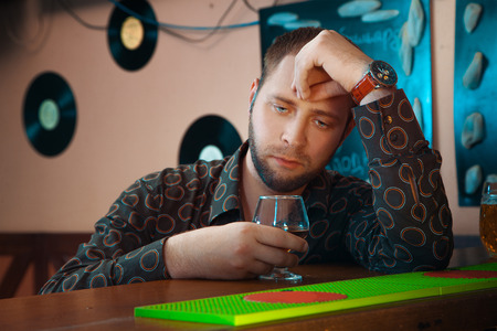 lonely man gets drunk in a bar with glass of brandy. horizontal photoの写真素材