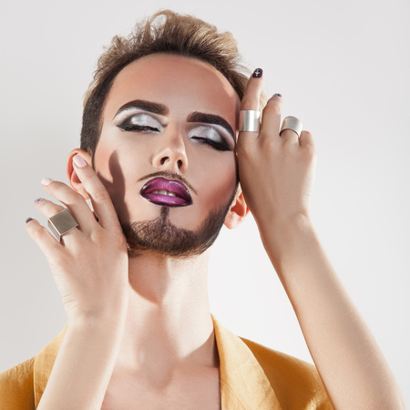 Sensual man with makeup and closed eyes in studio. grey background. square.の写真素材