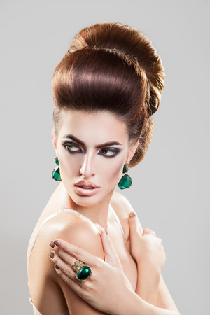 Portrait on grey background of young girl with creative hairstyle and nice accessories in studioの写真素材