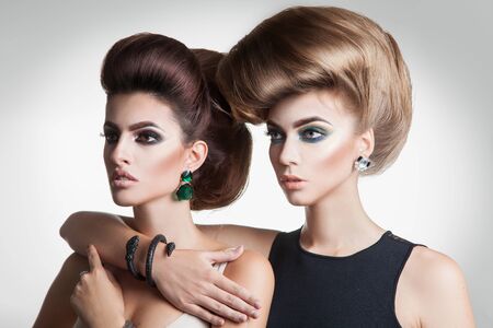 Closeup portrait of two beauty fashion women with creative volume hairstyle and nice makeup in studioの写真素材