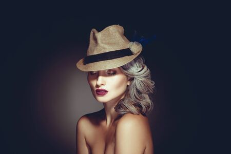 Photo of charming woman with grey hair color and beautiful makeup in hat in studio