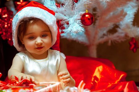 little girl unpacks the gift under the Christmas tree.の写真素材