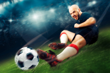 football player in action makes a tackle in the game. Soccer game. Professional football player. Championship league.の写真素材