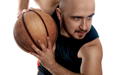 Close up portrait of serious basketball player on white background. Man with ball looking away. Basketballer. Horizontal photo of basketball player with ball in hands.の写真素材