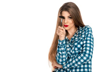 Horizontal portrait of fun makeup artist girl with brush in hand isolated on white background in studio. Makeup artist. Creative make up artist.の写真素材