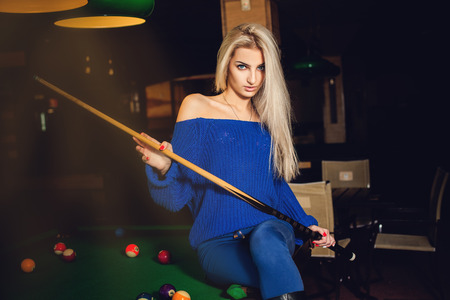 Fashion model posing on pool table with cue in hands.の写真素材