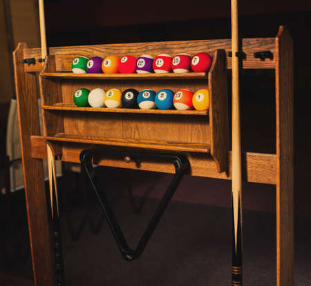 Set of balls for a game of pool billiards on shelves.